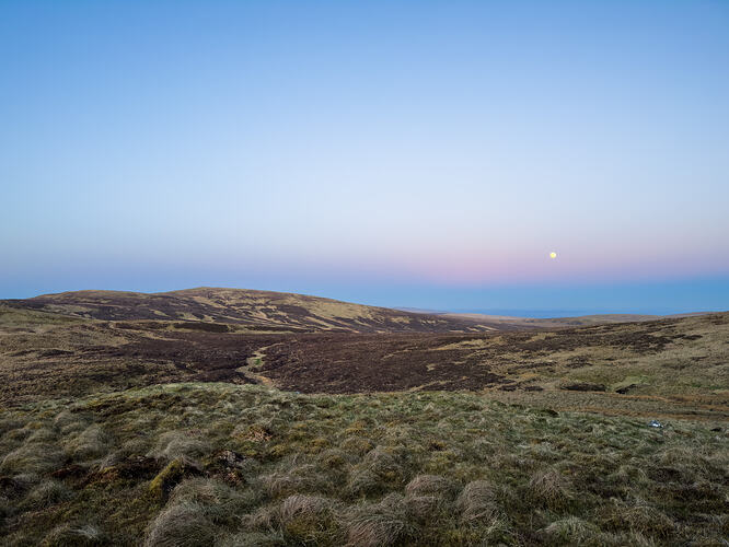 The moon in a purple sky, looking back towards Earl's Seat
