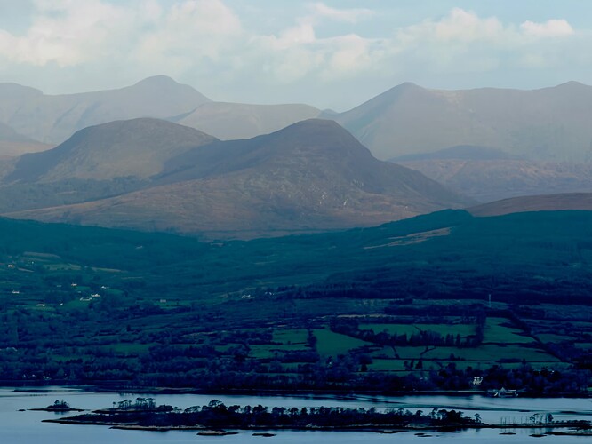 View north from Knocknagorraveela North East across Kenmare River. Dunkerron Island visible. The high mountains in the background are MacGillycuddy Reeks while the two round peaks closer to the bay are Boughill (right) and Cnoc na gCapall (left).