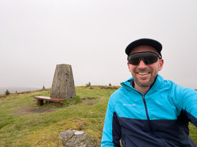 Selfie at the summit of Dun Colm with trig point behind