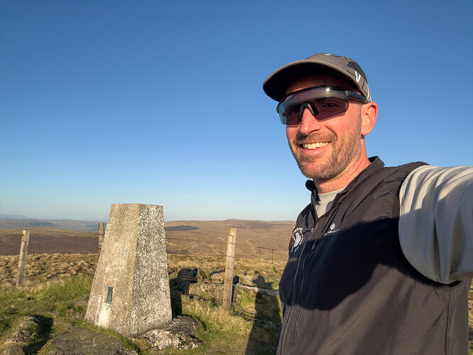 Selfie with the trig point and fence in the background